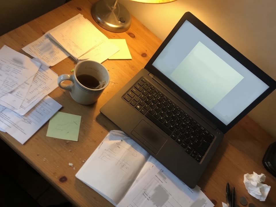 Escritorio de madera con portátil y papeles, el tipo de escena que uno captura para un ticket.