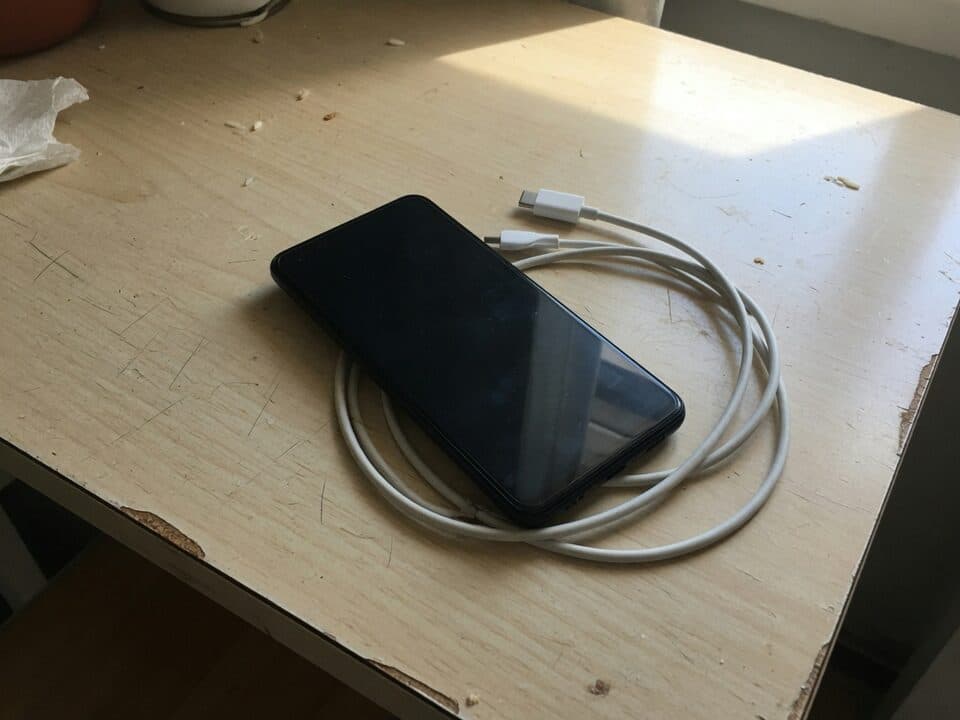Un teléfono boca arriba en la mesa de la cocina, con un cable USB-C enrollado al lado.